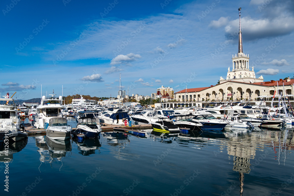 Sochi, Russia - November 23, 2020: Sochi, Russia - November 23, 2020: Sochi Commercial Sea Port. Main building of Marine Station. Motor ships and yachts on marinas. Close-up. Calm Black Sea.