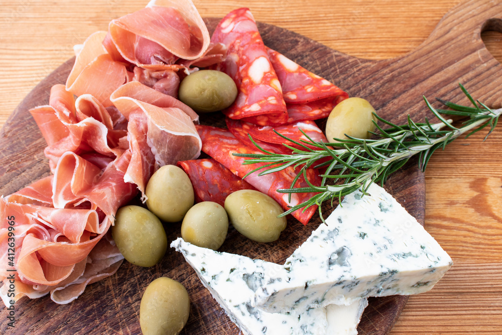 Assorted meat snacks. Prosciutto, chorizo sausage and olives on a wooden board. Assorted meat snacks. Prosciutto, chorizo sausage and olives on a wooden board.