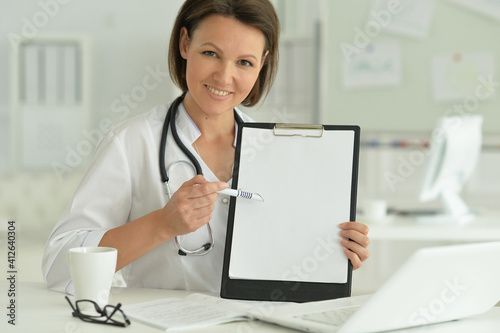 Portrait of  smiling female doctor  showing clipboard in hospital