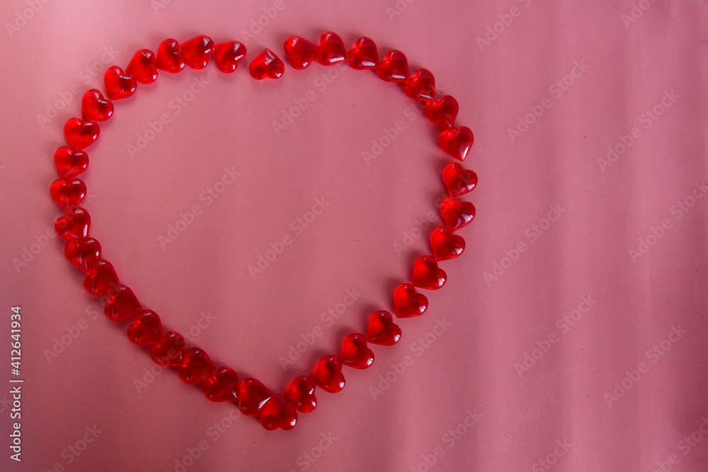 Red small hearts lined the outline of a large heart on a pink background. Place for text Red small hearts lined the outline of a large heart on a pink background. Place for text