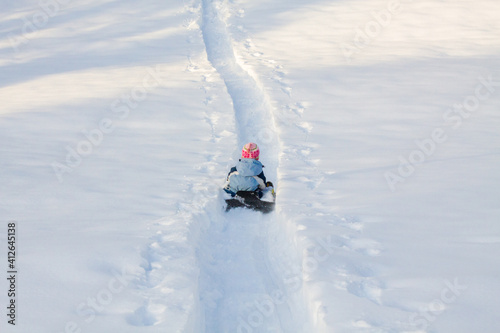 Mädchen fährt mit Schlitten durch tiefen Schnee