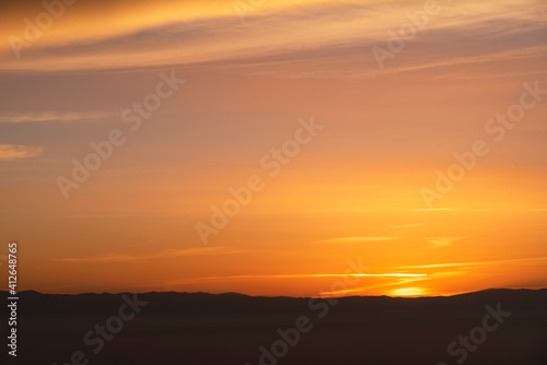 Beautiful panoramic bright sunset over the mountains silhouette.