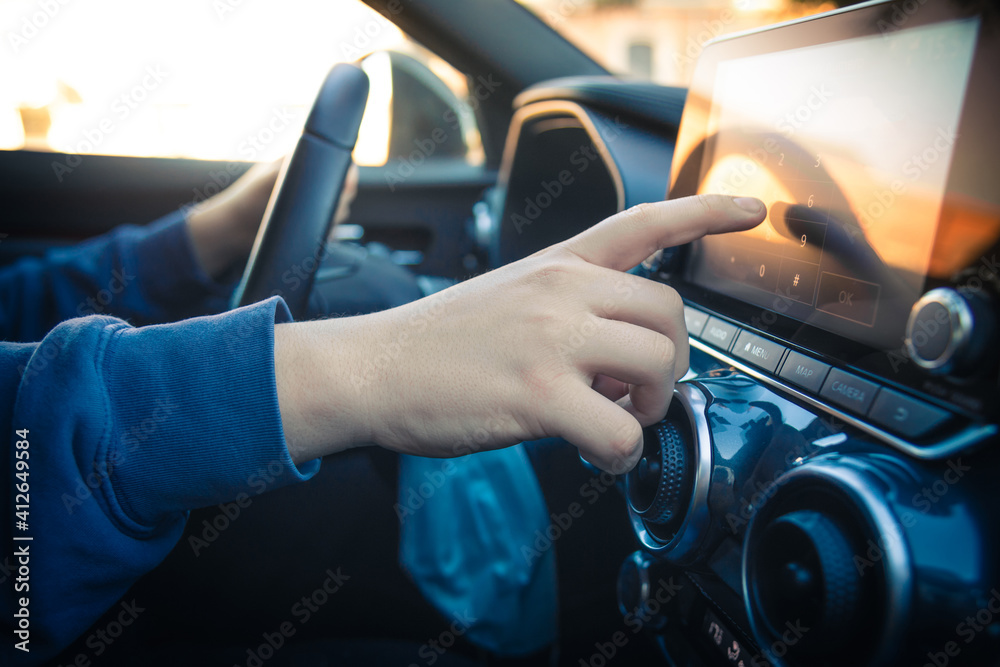 Teen drive a car and use infotainment. Young man reading messages and make phone call while driving. Dangerous behavior, accident risk. Danger, transgression, youth, distraction concept. Focus on hand