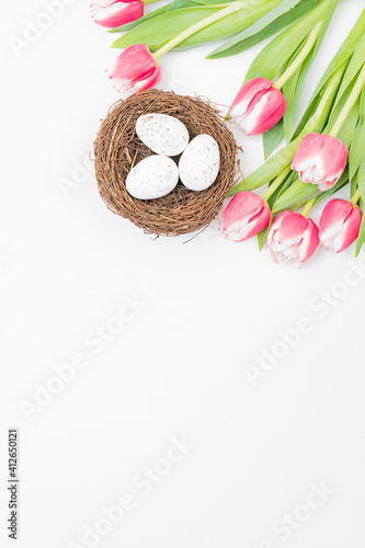 Flat lay easter composition with pink tulips and eggs on white background