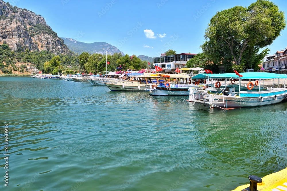 Turkey, Dalyan - June 2020: Row of empty tourist boat on the Dalyan river near famous Turkish landmark Dalyan town. Lycian tombs