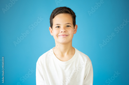 Portrait of happy young boy confident boy standing isolated on blue