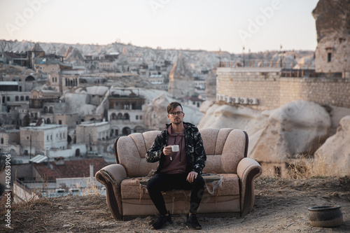 Minimal shot of a man sipping coffee on a sofa in a desert town