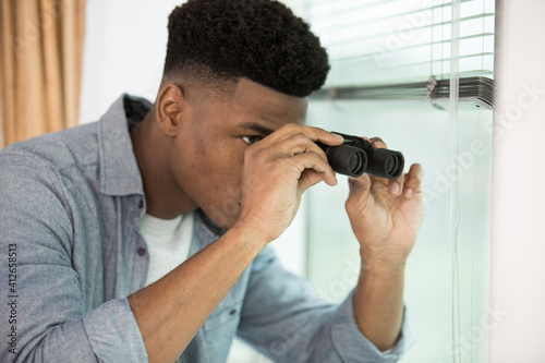 Fotografie young adult man spying at his neighbors