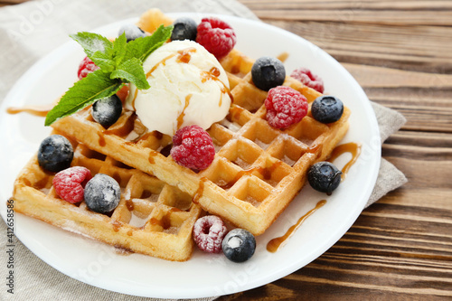 Tasty waffles with fresh berries and ice cream on brown wooden background photo