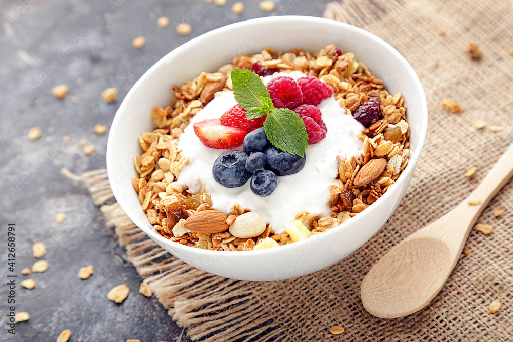 Tasty granola with fresh berries on grey background Tasty granola with fresh berries on grey background