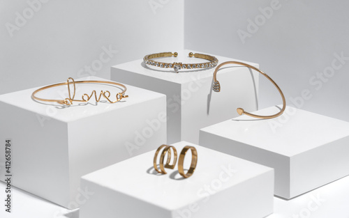 Golden bracelets and rings on white boxes with copy space photo