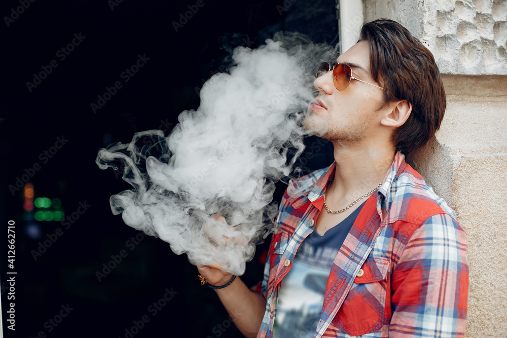 Stylish man in a city. Elegant male use the electronic cigarette