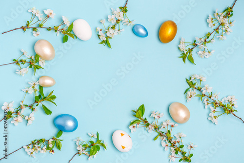 Colored eggs for Easter with branches of blossoming cherry on a blue background.