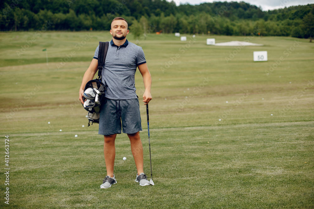 Obraz premium Man in a golf course. Male in a sport clothes. Guy playing golf