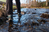 Detail picture of women's hiking boots crossing a river with the water flowing around them.