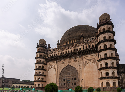 Vijayapura, Karnataka, India - November 8, 2013: Gol Gambaz Mausoleum. View in angle on brown building with its blackened domes and corner towers under gray cloudscape.