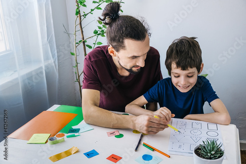 Autistic boy during therapy at home with his father with learning and having fun together. Autism awareness concept photo