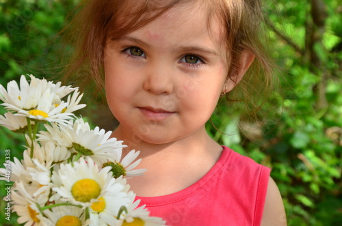 Cute little smiling girl in the bouquet of chamomile field in spring or summer, happy childhood, mother's day