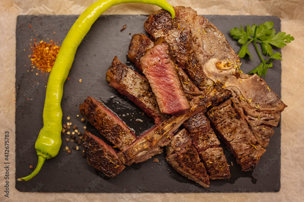 Foto de Tbone grilled beef steak with spices and herbs. TBone Steak