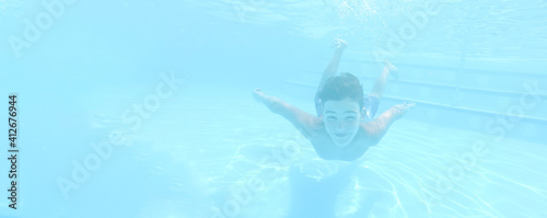 Boy swimming under blue water in pool © artemidovna