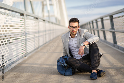 Hipster business casual male relaxing outdoors on the bridge. Yuppie or entrepreneur enjoying outside