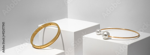 Fotografia, Obraz Panoramic shot of Two golden bracelets on white geometric background