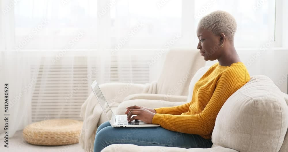 Happy woman using laptop on sofa at home Happy woman using laptop on sofa at home