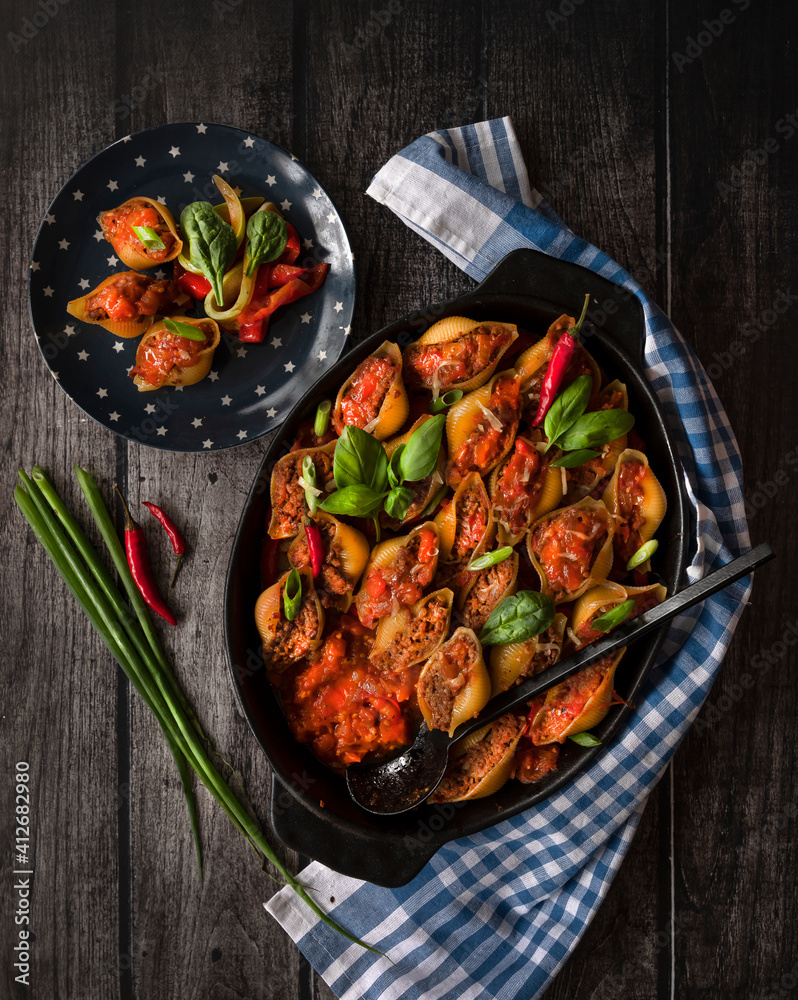Conchiglioni stuffed with minced meat and baked in tomato sauce, close-up, top view. Conchiglioni stuffed with minced meat and baked in tomato sauce, close-up, top view.