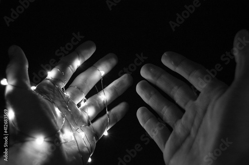 Two hands on black background one hand glowing in wire another free in dark photo