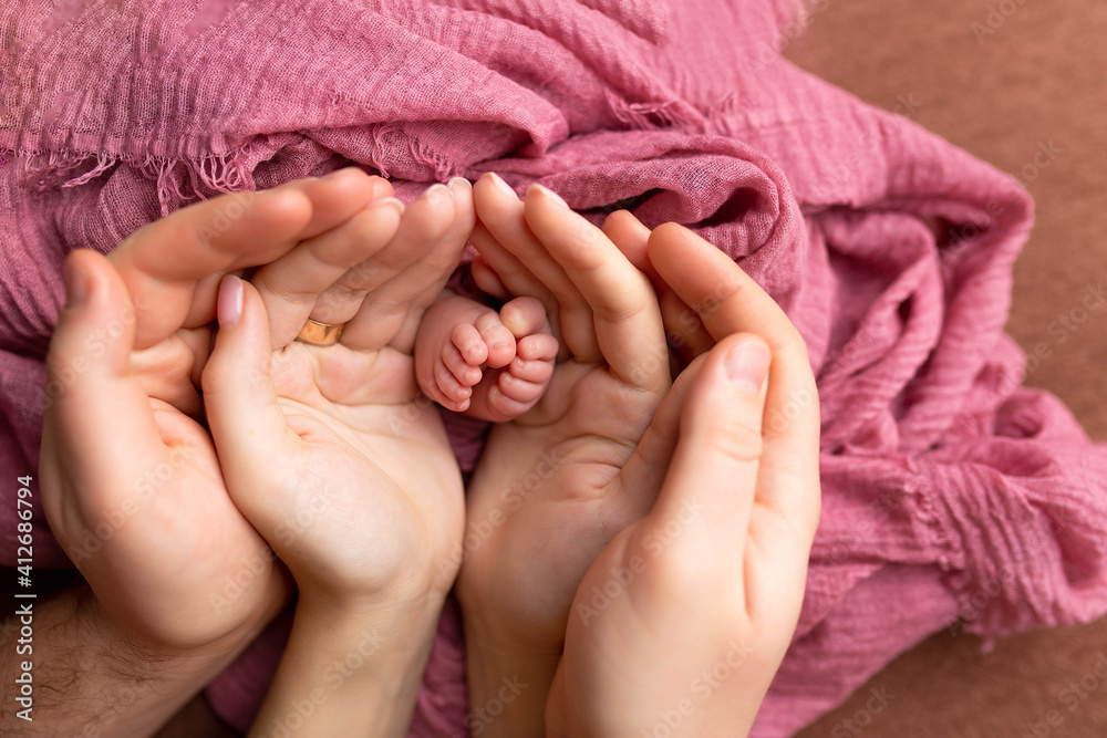 feet of a newborn baby in the hands of mom and father. baby feet