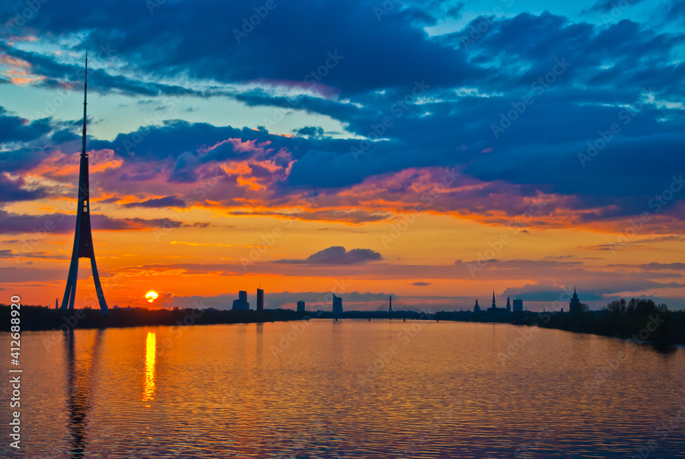 sunset. in the photo, the clouds are illuminated by the evening sun,in the foreground is a river, in the background is a city