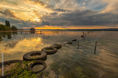 Beautiful sunset on the lake with fishing net in water and old tires