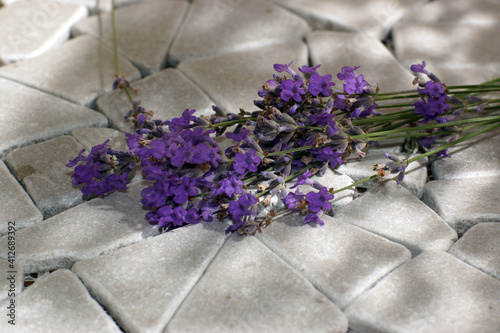 A bouquet of lavender lies on gray tiled stones in openwork shade