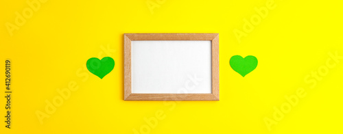 Green paper hearts flat lay mockup, banner on wooden frame in the centre with white copy space on yellow background Saint Patrick's Day 17 march traditional spring celebration holiday and good luck photo