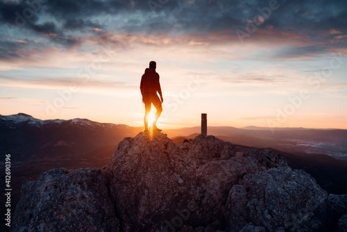 PERSON STANDING AT THE TOP OF A MOUNTAIN. MAN ENJOYING AND HAVING FUN DURING SUNSET. OUTDOOR AND SUNSET CONCEPT. © EDGAR
