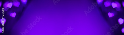 Banner of purple and violet lights makes hears shape bokeh at the left and right. Romantic, love, Valentines day relationship dark background concept with copy space