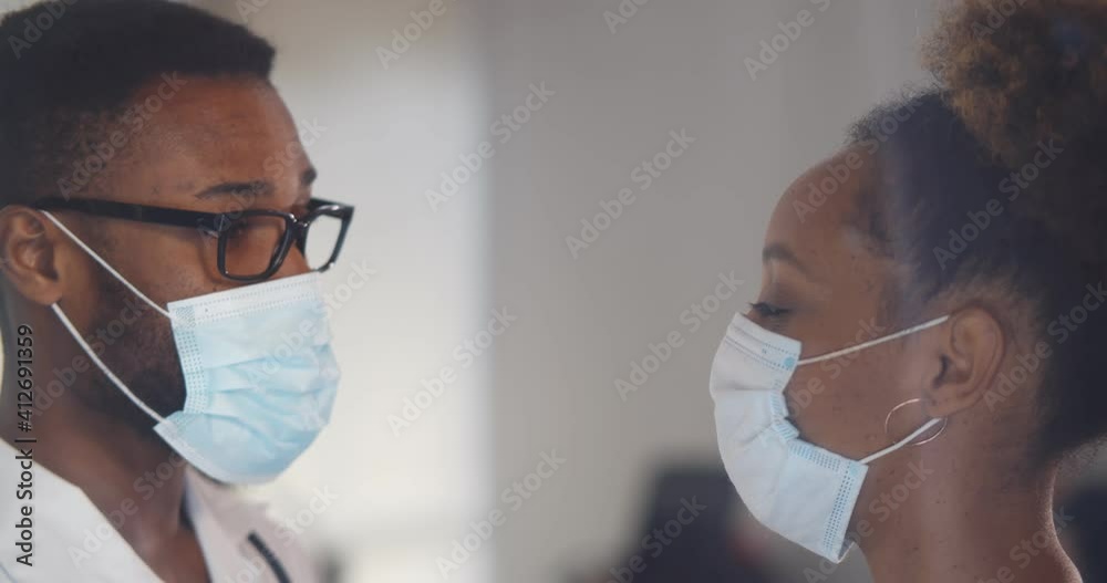 Close up of afro-american doctor in safety mask talking to female patient Close up of afro-american doctor in safety mask talking to female patient