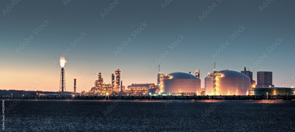Fototapeta premium Fertilizer plant in an agricultural landscape at sunset. Railroad tanker cars stretched across the image. 