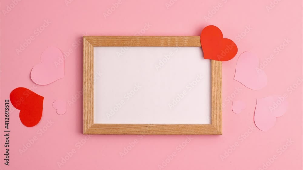 Stop motion animation mockup  of red and pink paper hearts on and near wooden frame on pink background Valentines day love relationship romantic anniversary wedding holiday concepts Flat lay