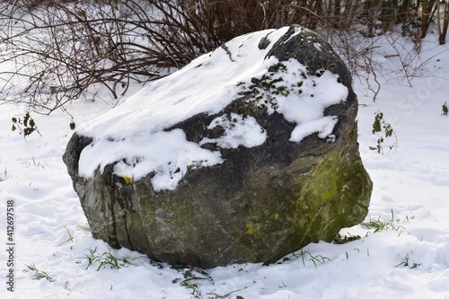Decorative stone covered with snow in the park. 
