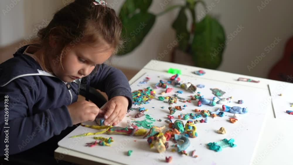 Cute little girl having fun with colorful modeling clay at a daycare. Creative kid molding at home. Child play with plasticine Cute little girl having fun with colorful modeling clay at a daycare. Creative kid molding at home. Child play with plasticine