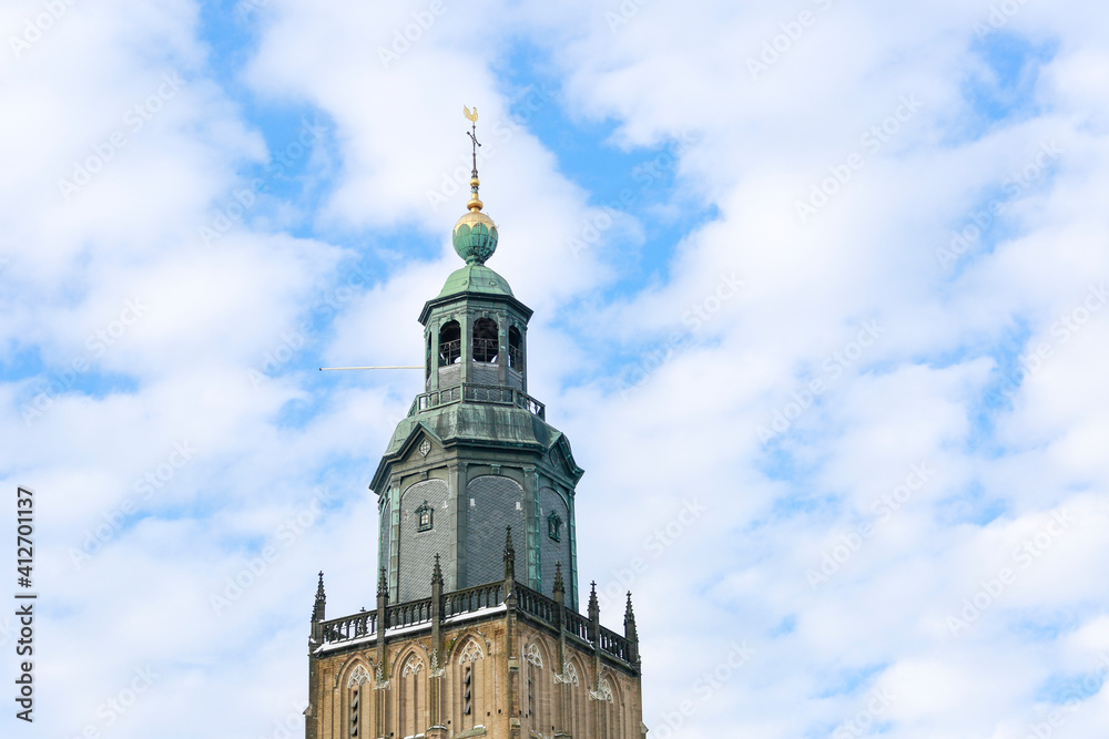 Top of the Walburgiskerk tower against a blue sky with wave pattern clouds