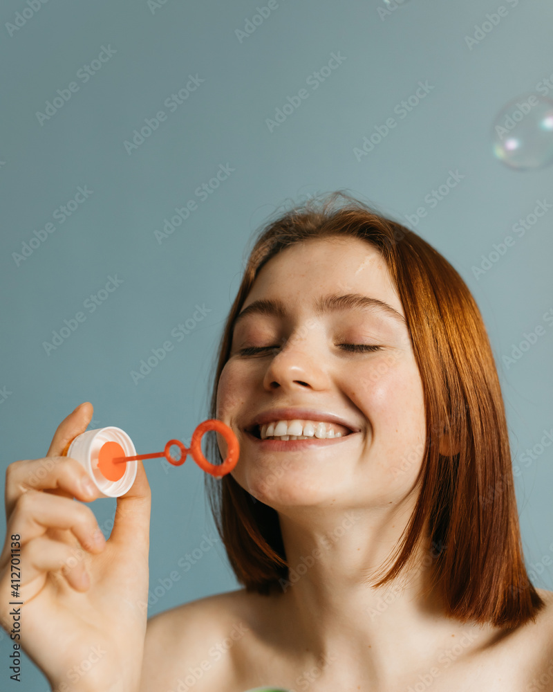 Model with naked shoulders smiling and blowing bubbles Model with naked shoulders smiling and blowing bubbles