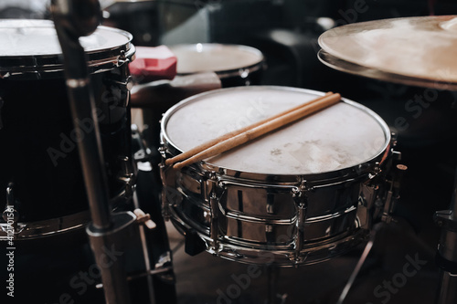 Two wooden drumsticks are on the drum kit near the cymbals close up. The concept of a musician, jazz band and rock band.