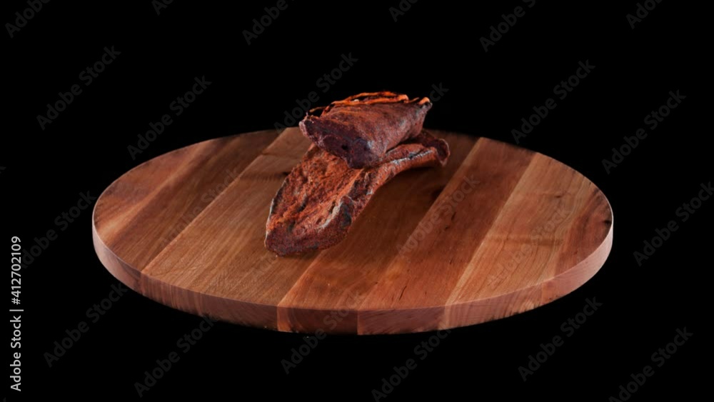 Meat raw smoked sausage on wooden round board on black isolated background, several sticks and pieces Meat raw smoked sausage on wooden round board on black isolated background, several sticks and pieces