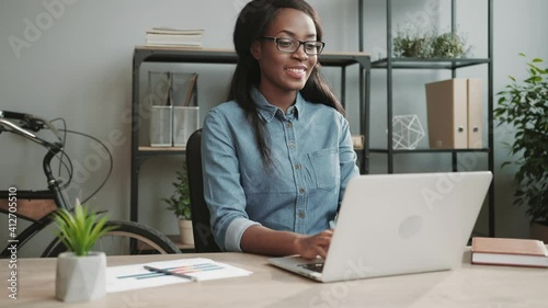 Successful businesswoman working at laptop sitting in modern office satisfactorily nodding her head in sign of successful deal.