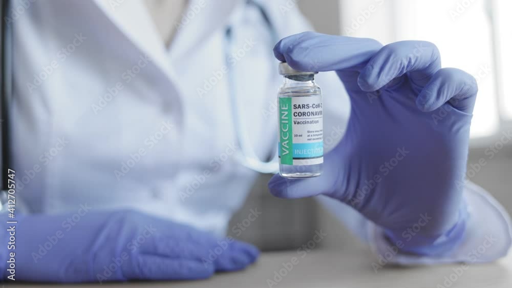 Vaccine dose close up. Presentation of vaccine from COVID-19 coronavirus. Doctor holds in his hand a vial bottle with an invented vaccine. Global pandemic finishes. Vaccine dose close up. Presentation of vaccine from COVID-19 coronavirus. Doctor holds in his hand a vial bottle with an invented vaccine. Global pandemic finishes.