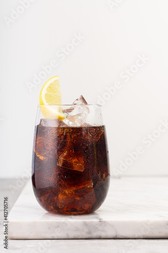 Photography Glass of cola with ice and lemon on the white background, vertical