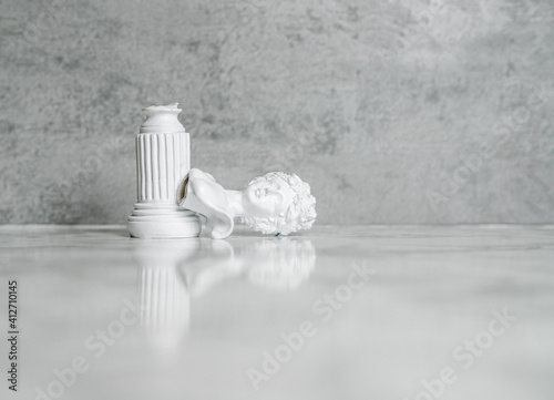 A plaster bust of a woman fell from a pedestal and broke off. Plaster head on a gray background. A space for insertion. Concept it hurts to fall off a pedestal. Copy space