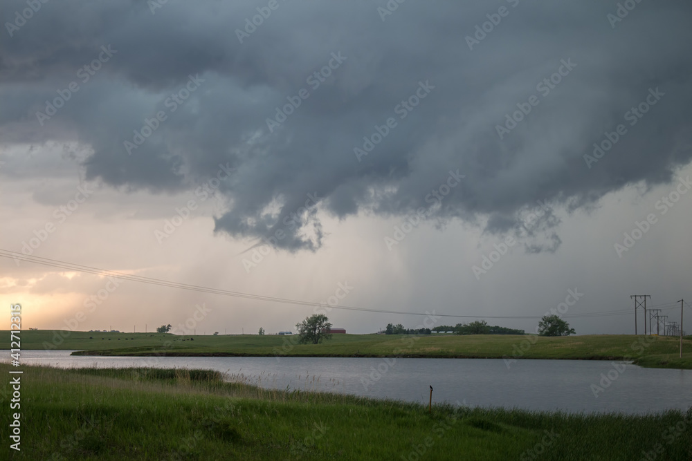 A tornado forms beneath a supercell storm with funnel cloud reaching towards the ground. A tornado forms beneath a supercell storm with funnel cloud reaching towards the ground.